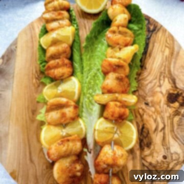 Smoked scallops on skewers on a bed of lettuce with lemons, presented as a delicious recipe.
