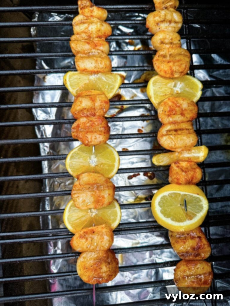Another view of scallops and lemon slices on a skewer, smoking on a Traeger grill, showcasing the rich smoke.