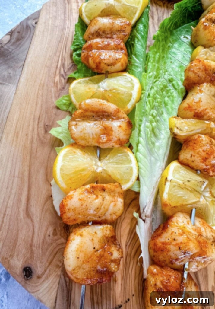 Smoked scallops on skewers, beautifully plated on a bed of fresh green lettuce with lemon wedges, ready to be served.