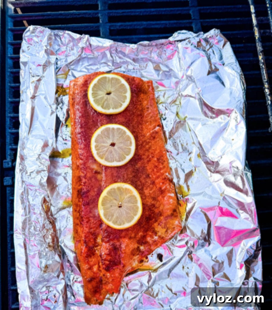 salmon in foil on a grill with fresh lemons