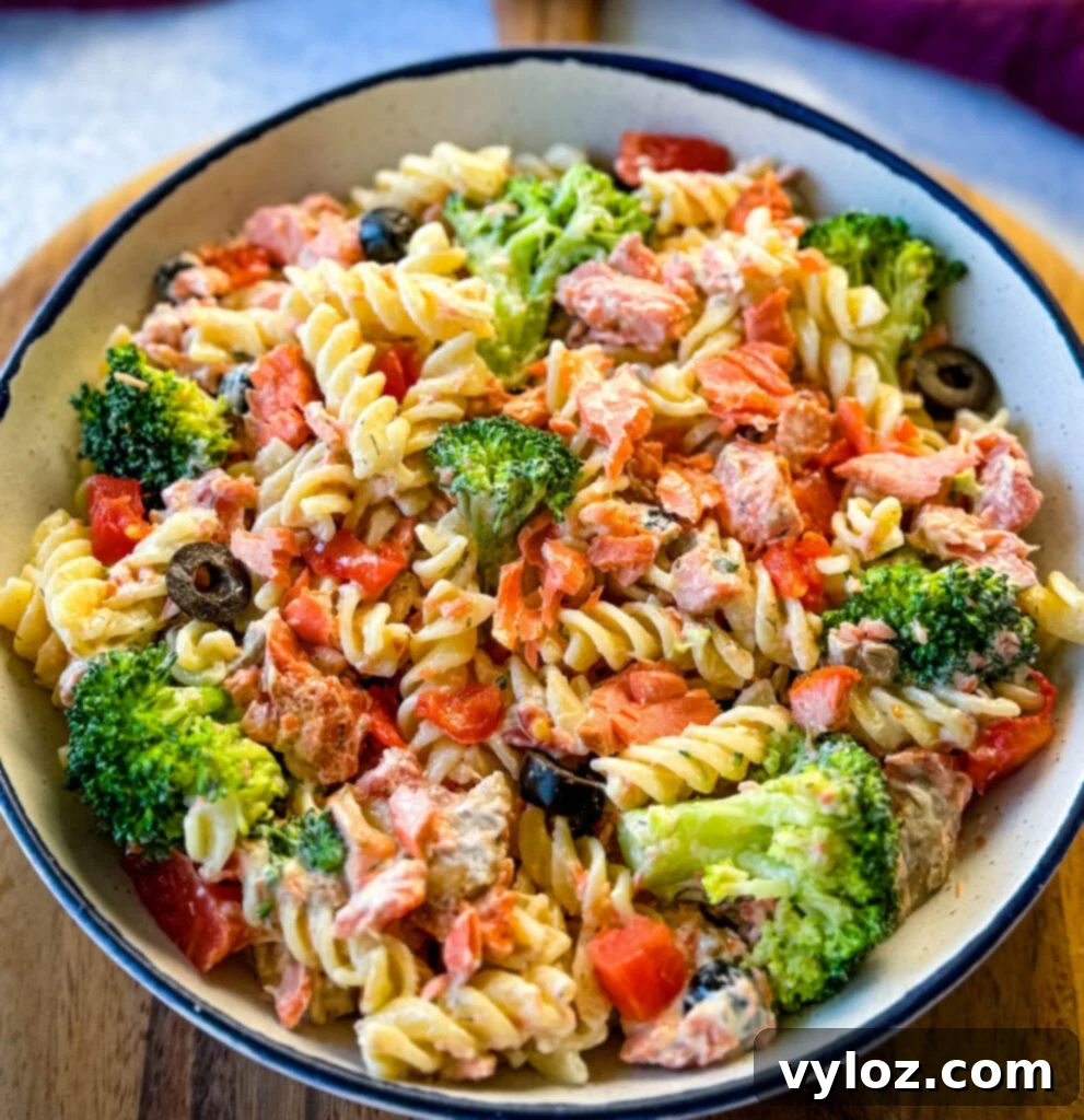salmon pasta salad with broccoli and tomatoes in a white bowl