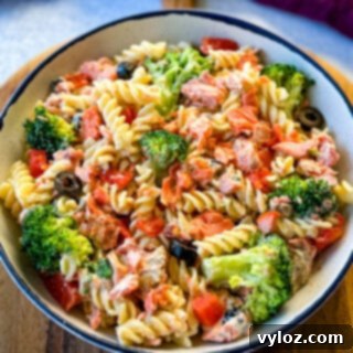 salmon pasta salad with broccoli and tomatoes in a white bowl