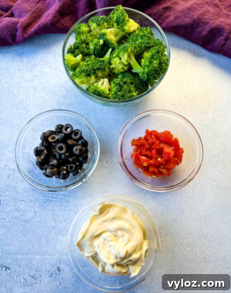 broccoli, olives, tomatoes, and mayo in separate glass bowls