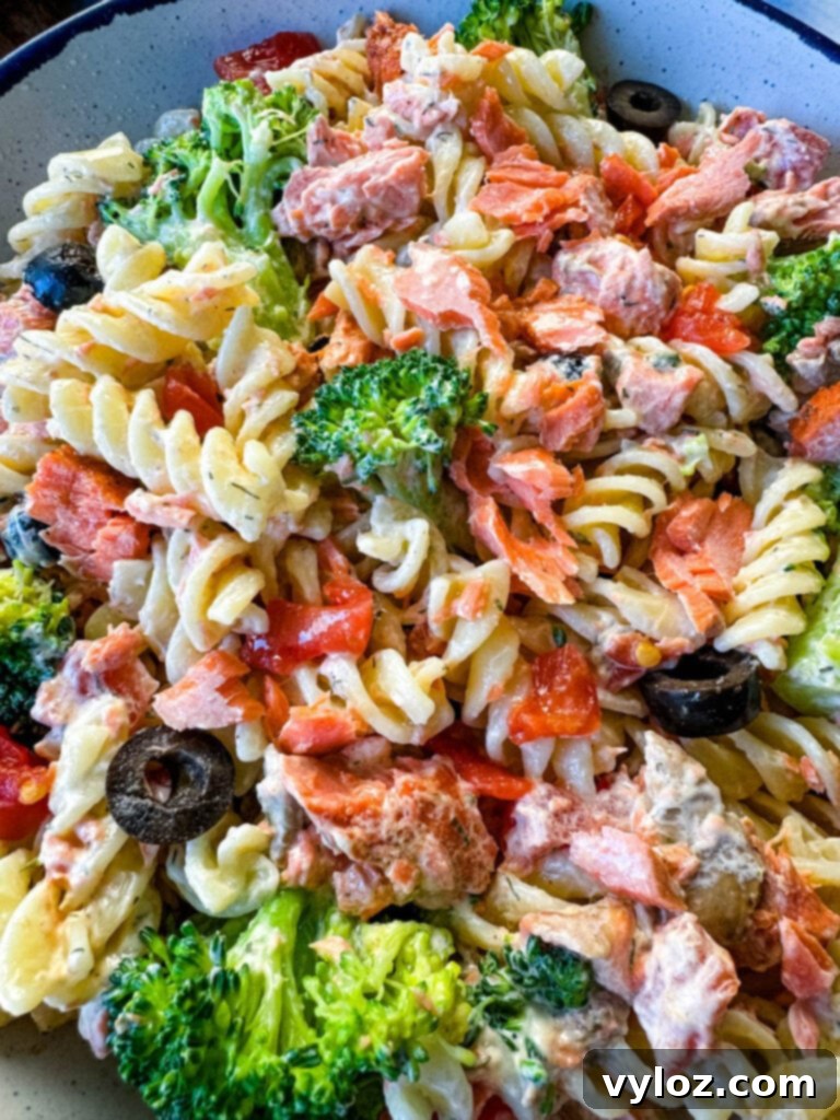 salmon pasta salad with broccoli and tomatoes in a white bowl