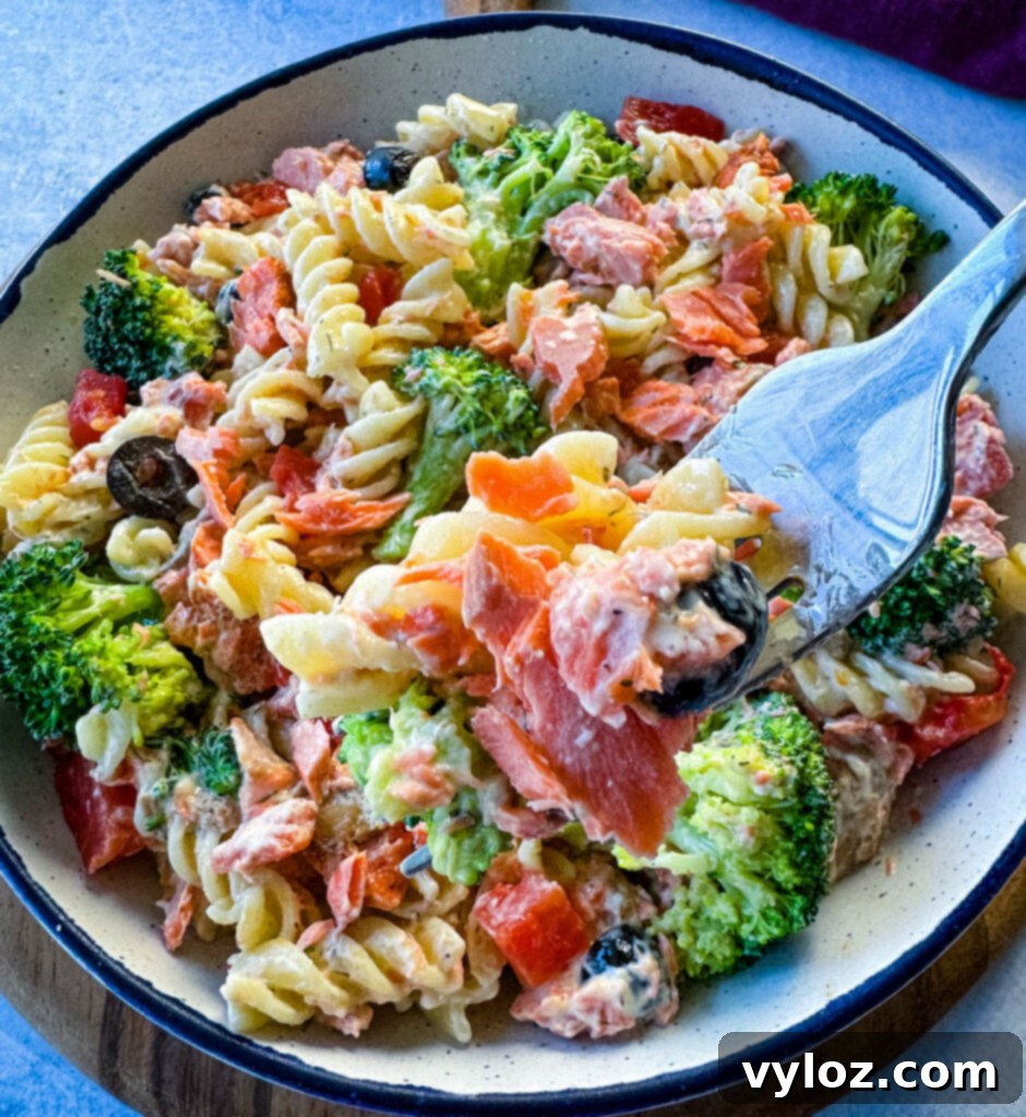 a forkful of salmon pasta salad with broccoli and tomatoes
