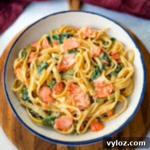 Salmon Fettuccine Alfredo with spinach in a white bowl