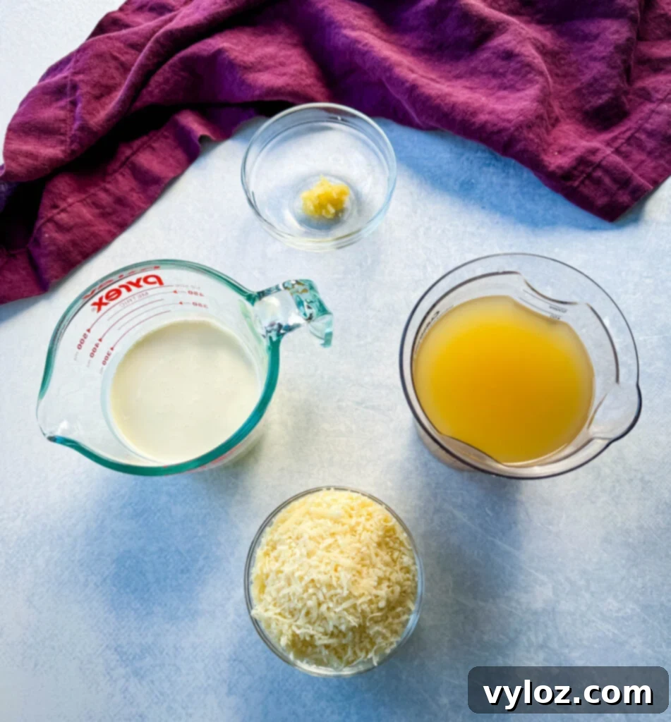 Minced garlic, heavy cream, chicken broth, and grated Parmesan cheese in separate glass bowls, ready for cooking.