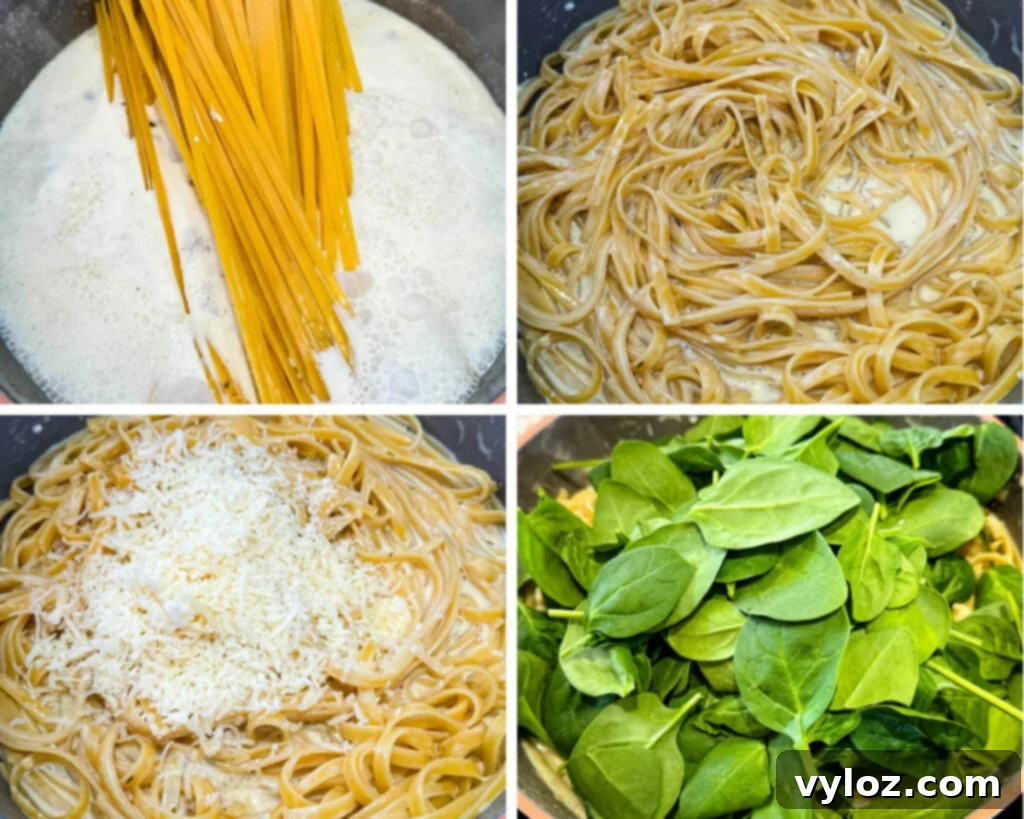 Cooked fettuccine pasta with creamy Alfredo sauce and fresh spinach simmering in a large skillet.