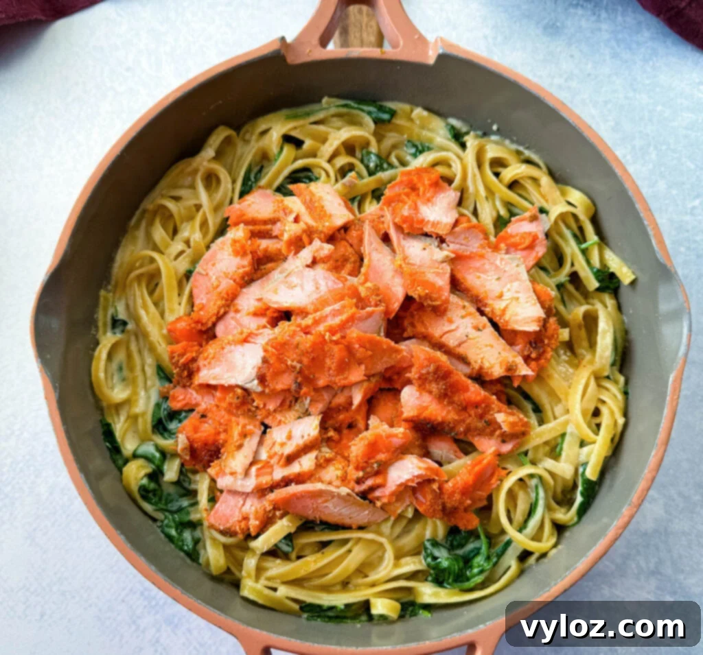Salmon Fettuccine Alfredo with spinach in a pan, fully assembled and ready to serve.