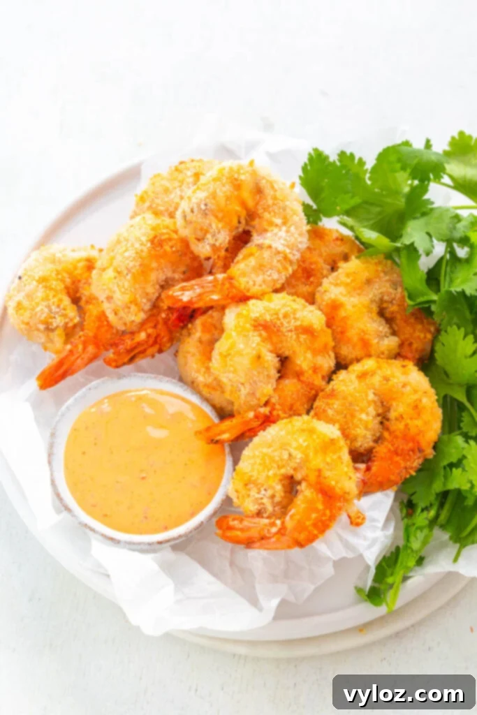 Crispy air fryer bang bang shrimp on a white plate with fresh lettuce