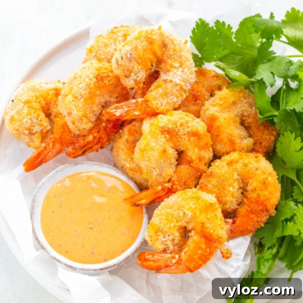Beautifully presented air fryer Bang Bang Panko Breaded Fried Shrimp on a white plate, served with a spicy sweet chili sauce