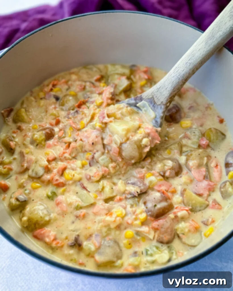 Creamy salmon chowder with corn and potatoes simmering in a large Dutch oven.
