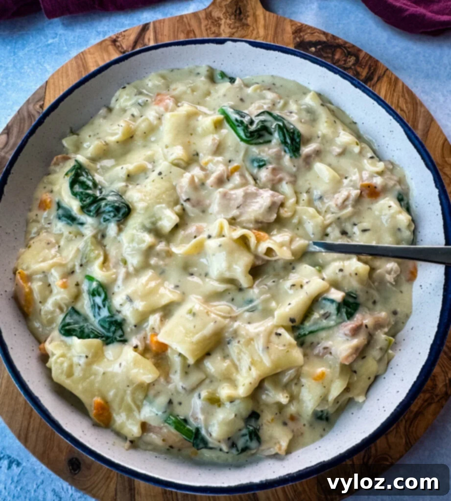 Creamy White Lasagna Soup 2 A bowl of creamy White Lasagna Soup with visible carrots, celery, and spinach, garnished with fresh herbs.