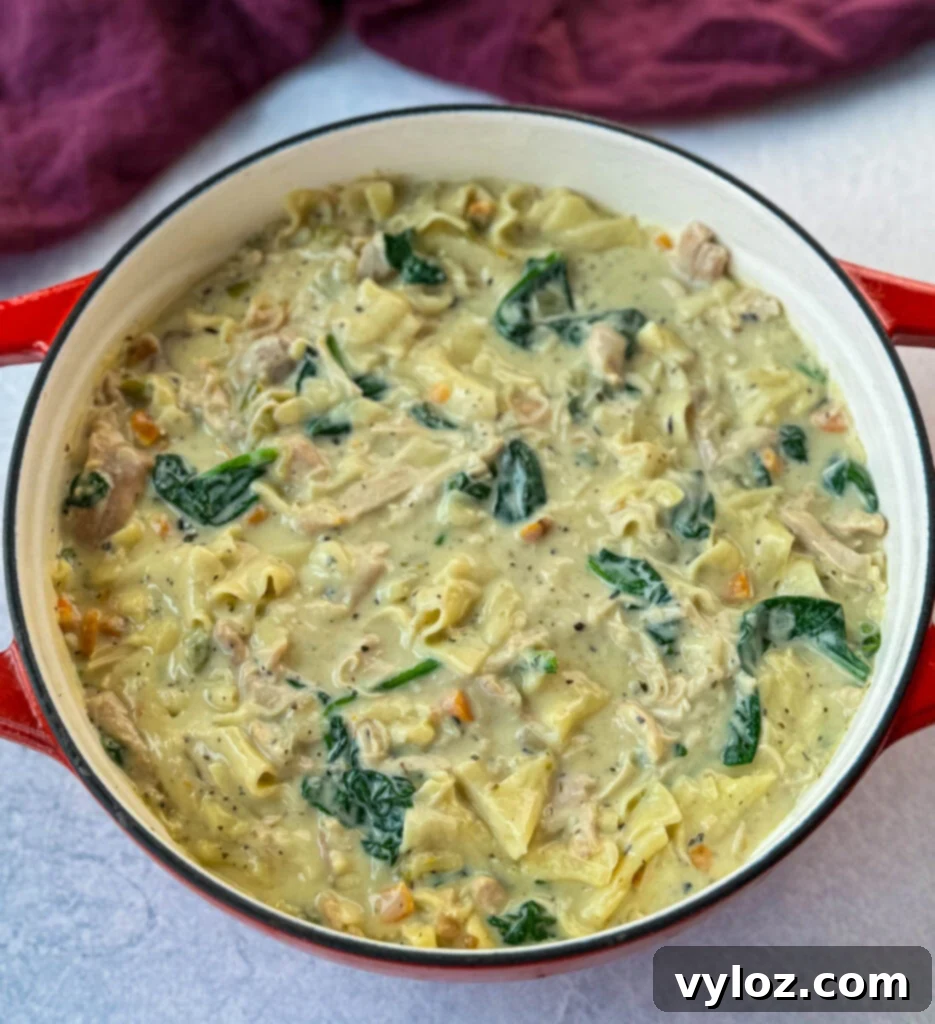 Creamy White Lasagna Soup 12 Creamy white lasagna soup simmering in a Dutch oven with visible carrots, celery, and spinach.