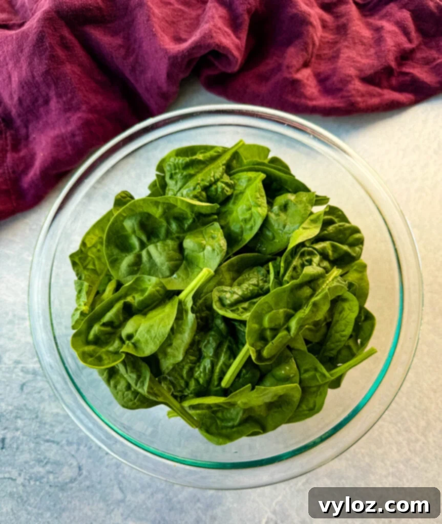 Creamy White Lasagna Soup 5 A bowl filled with fresh, vibrant green spinach, ready to be added to the soup.