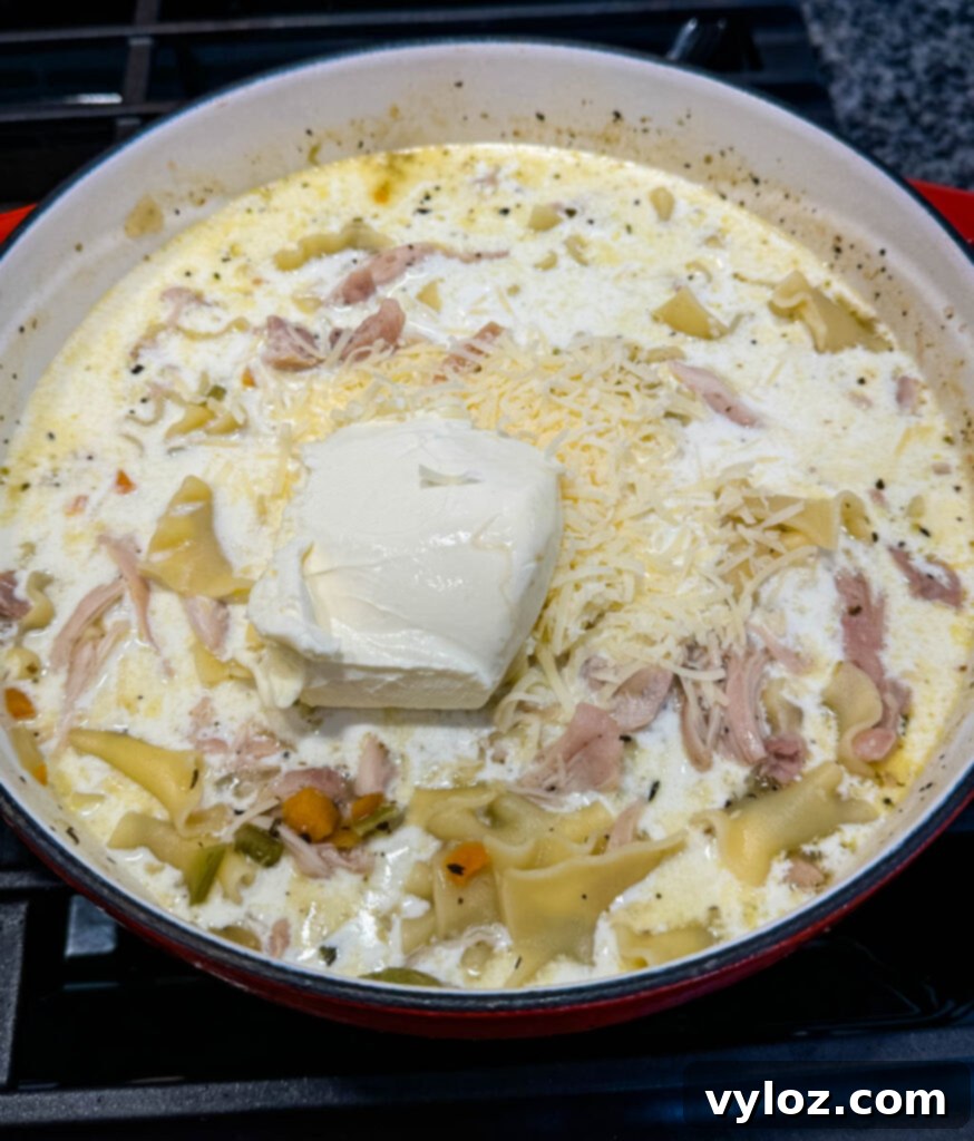 Creamy White Lasagna Soup 10 White Lasagna Soup in a Dutch oven with cream cheese melting in, illustrating the creaming process.
