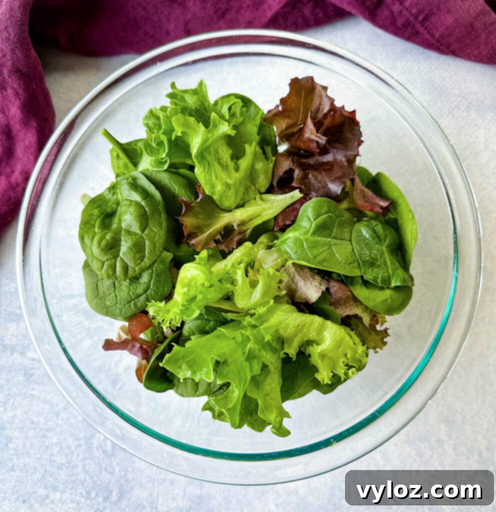 Zesty Shrimp Taco Bowl 5 A vibrant assortment of fresh salad greens neatly arranged in a clear glass bowl, showcasing their crisp texture and varied colors.