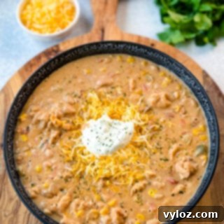 White chicken chili served in a black bowl with sour cream and grated cheese on top, ready for a comforting meal.