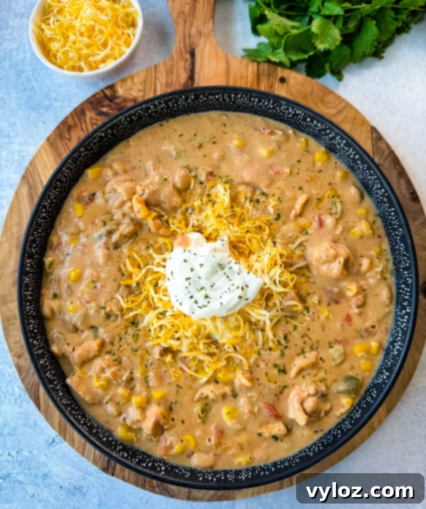 A inviting black bowl filled with creamy white chicken chili, generously topped with sour cream and freshly grated cheese, ready to be enjoyed.