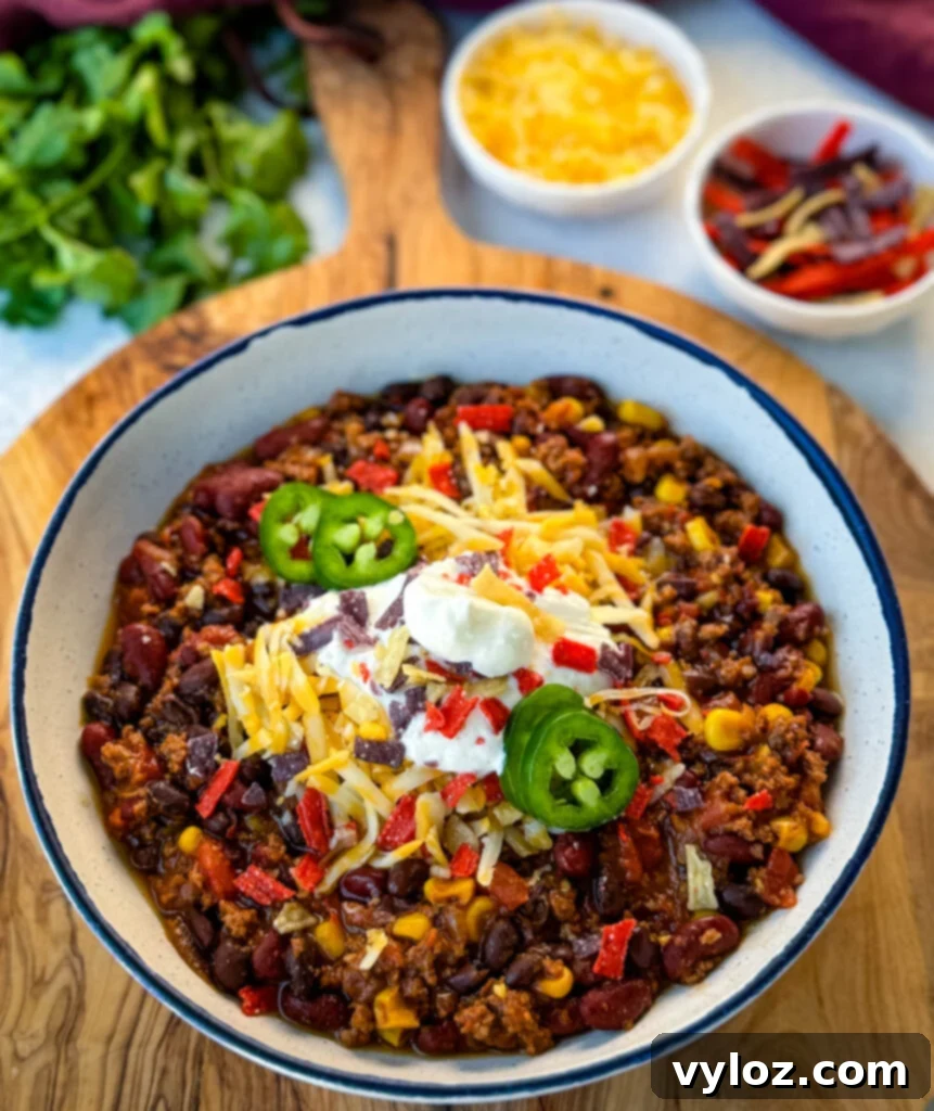 Taco Chili 2 beef taco chili in a white bowl with jalapenos, sour cream, shredded cheese, and tortilla chips