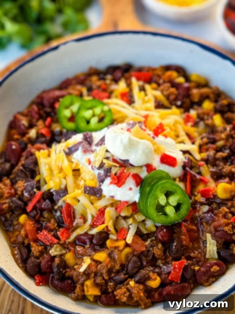 Taco Chili 9 beef taco chili in a white bowl with jalapenos, sour cream, shredded cheese, and tortilla chips