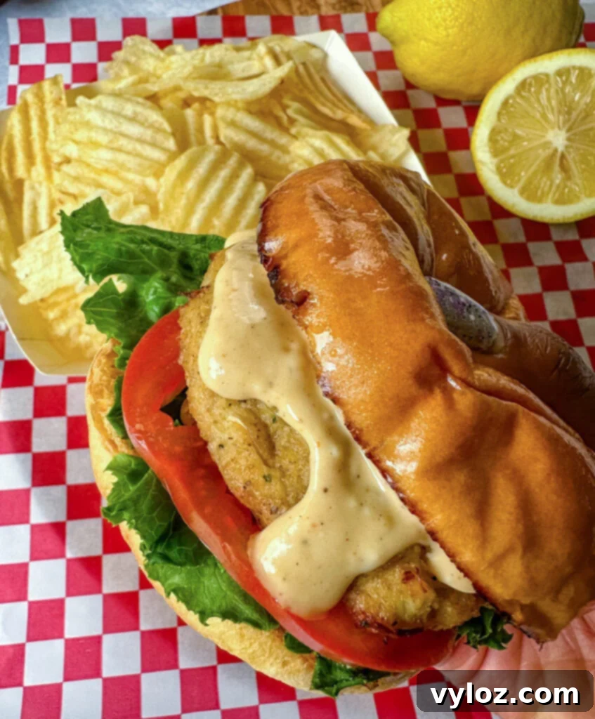 person holding crab cake sandwich with chips