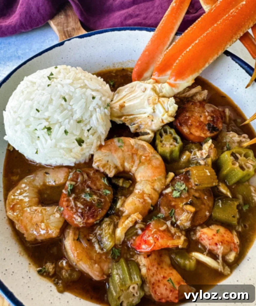 A generous serving of Cajun seafood gumbo featuring shrimp and crab meat, with prominent crab legs and a side of rice, presented beautifully in a white bowl.
