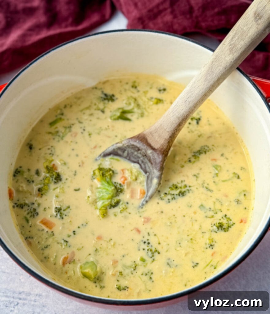 Velvety Broccoli Cheddar Soup 6 broccoli cheddar soup in a Dutch oven with a wooden spoon