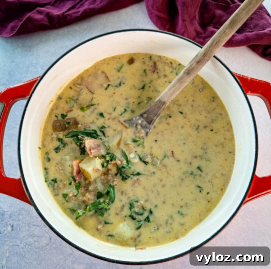 Hearty Italian Sausage and Kale Soup 7 Italian sausage soup with potatoes and kale in a Dutch oven with a wooden spoon