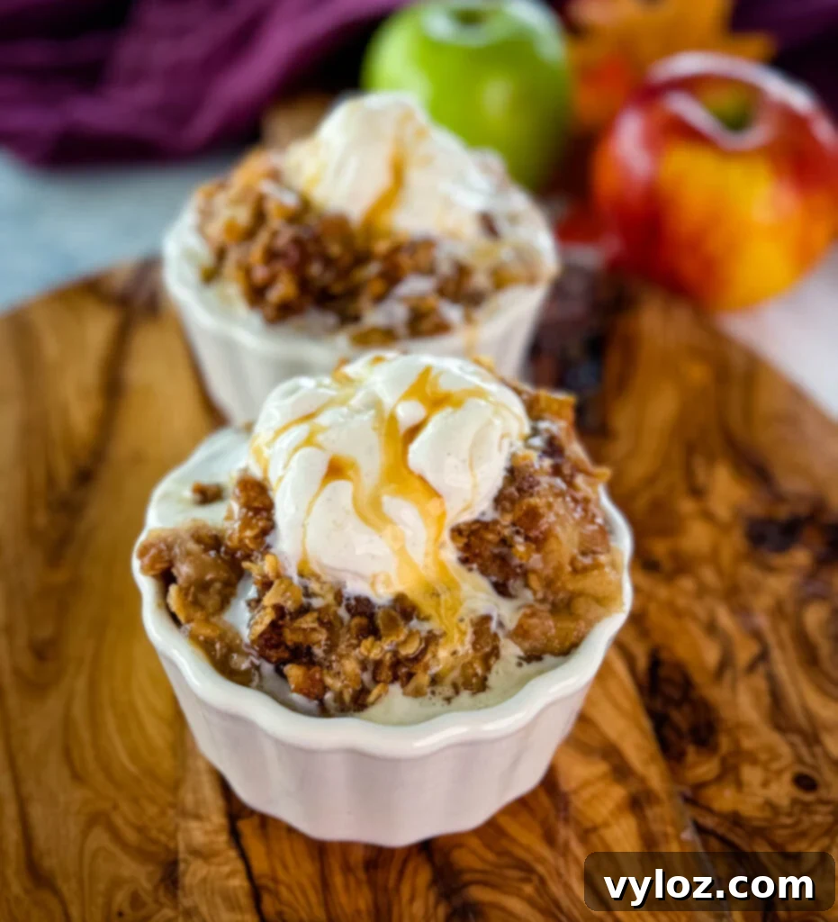 Effortless Crockpot Apple Crumble 10 slow cooker Crockpot apple crisp in a white bowl with a scoop of vanilla ice cream and caramel