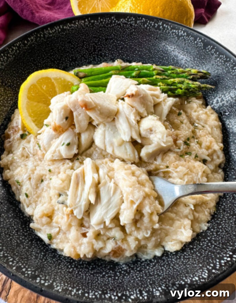 crab risotto in a black bowl with fresh lemon and asparagus