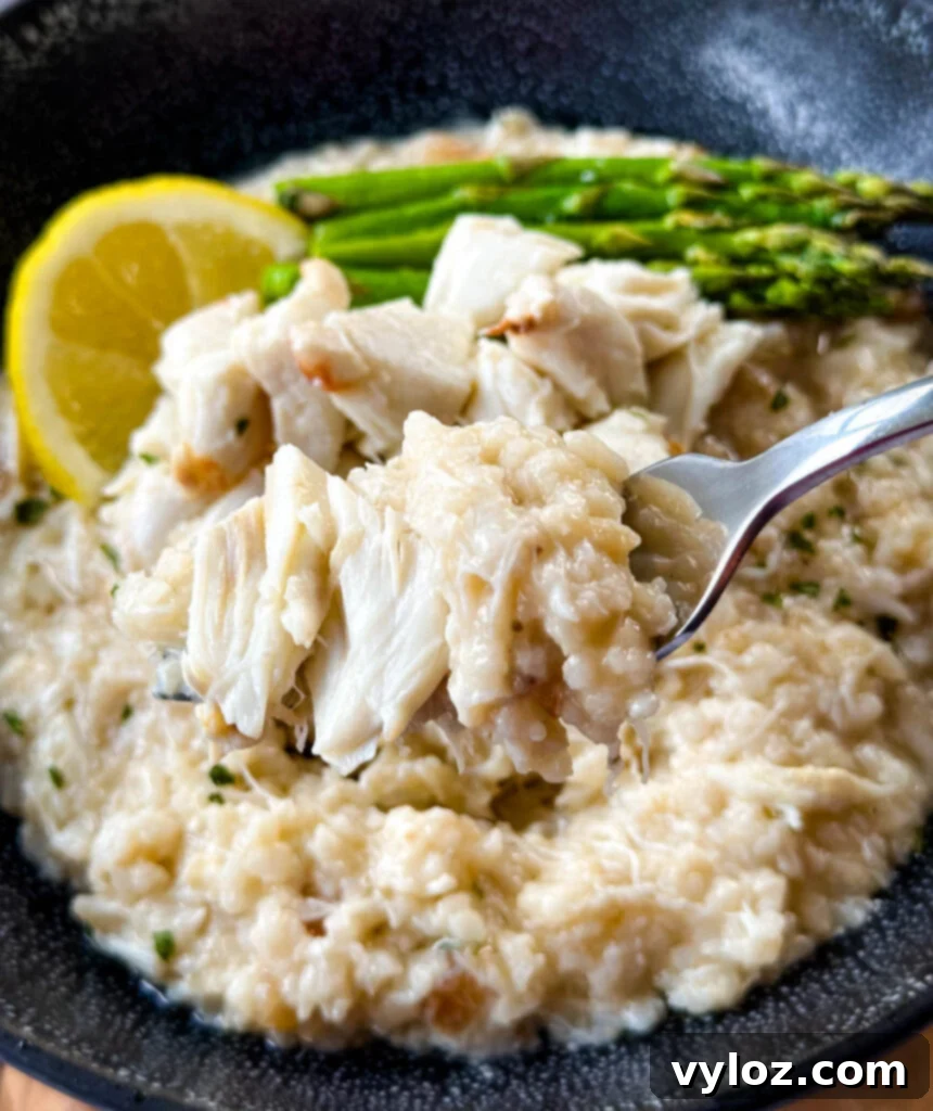 a fork full of crab risotto in a black bowl