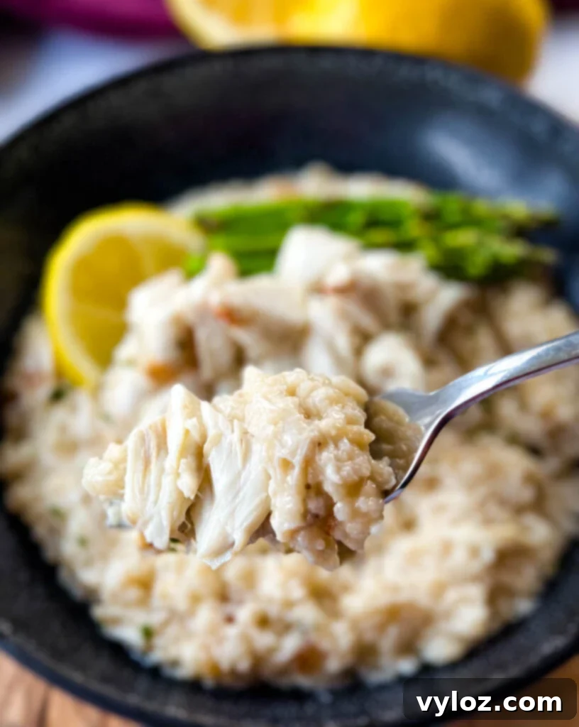 a fork full of crab risotto in a black bowl