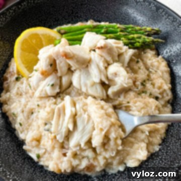 crab risotto in a black bowl with fresh lemon and asparagus