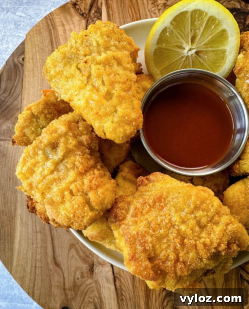 Simple Catfish Nuggets 11 breaded catfish nuggets on a plate with hot sauce and a fresh lemon