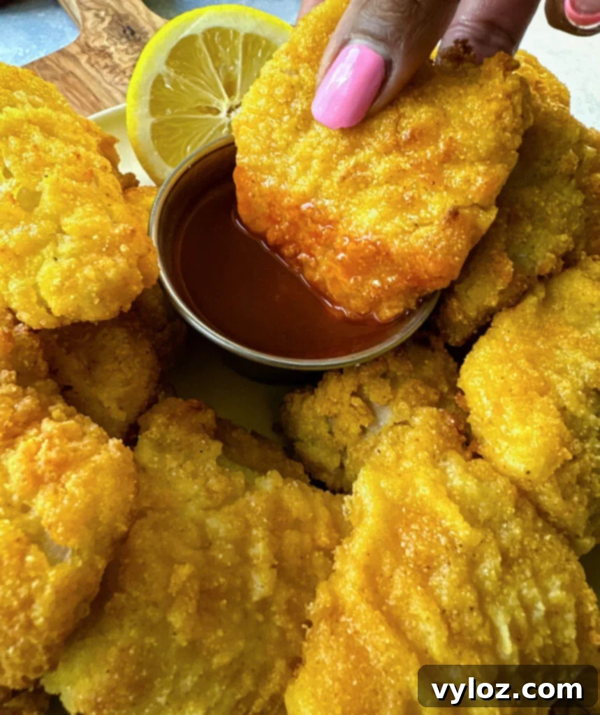 Simple Catfish Nuggets 13 person holding catfish nugget dipped in hot sauce