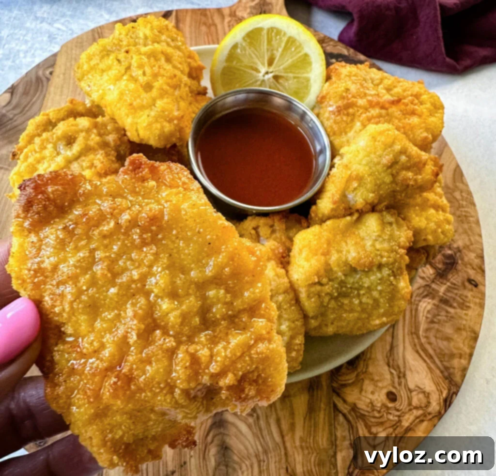 Simple Catfish Nuggets 14 breaded catfish nuggets on a plate with hot sauce and a fresh lemon