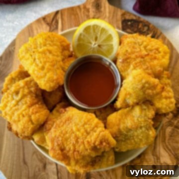 Simple Catfish Nuggets 15 breaded catfish nuggets on a plate with hot sauce and a fresh lemon