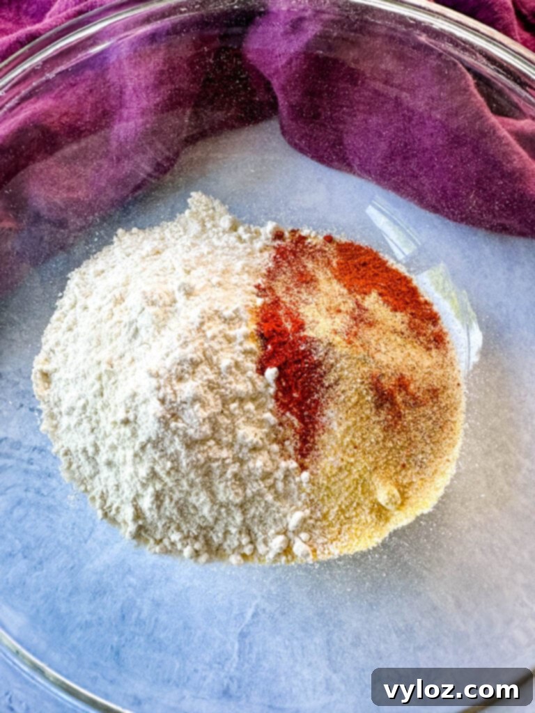 Crispy Fish Fry Mix 4 A glass bowl filled with a mixture of cornmeal, flour, and various spices, ready for breading.