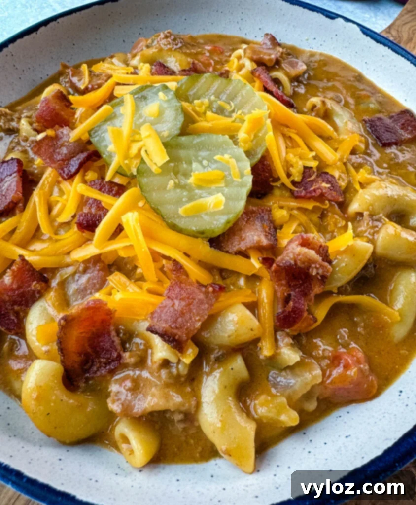 Savory Bacon Cheeseburger Mac Soup 2 bacon cheeseburger soup with pickles and grated cheese in a white bowl