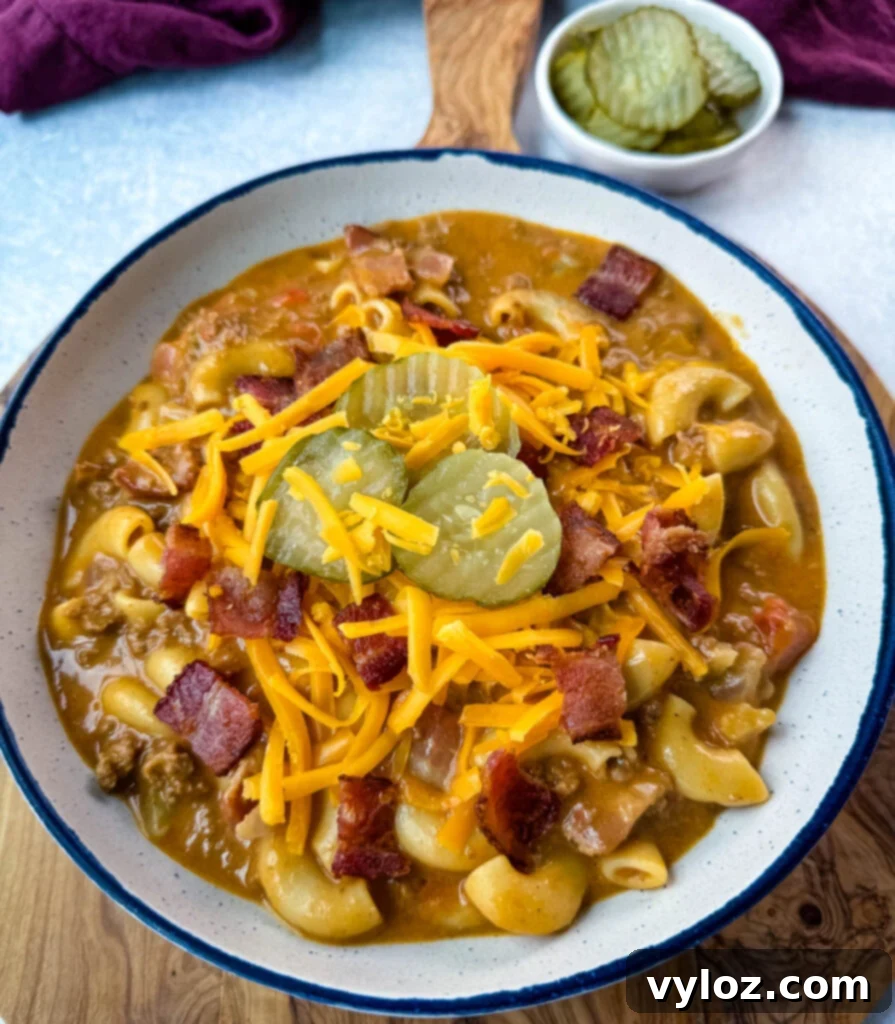 Savory Bacon Cheeseburger Mac Soup 11 bacon cheeseburger soup with pickles and grated cheese in a white bowl
