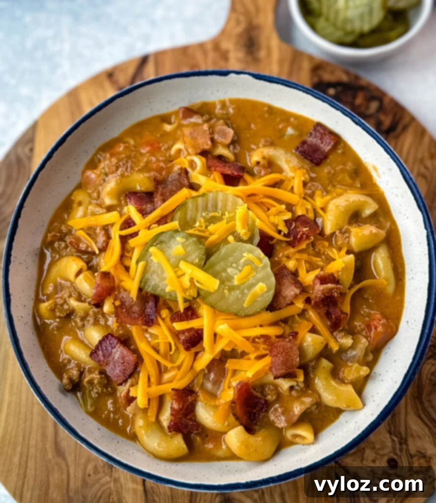 Savory Bacon Cheeseburger Mac Soup 13 bacon cheeseburger soup with pickles and grated cheese in a white bowl