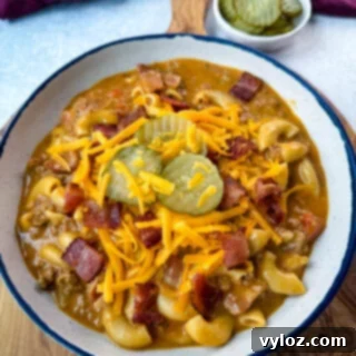Savory Bacon Cheeseburger Mac Soup 14 bacon cheeseburger soup with pickles and grated cheese in a white bowl
