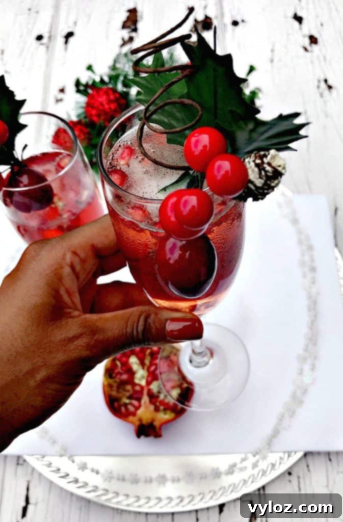 Ruby Red Holiday Fizz 8 Close-up of a hand reaching for a Pomegranate Holiday Mimosa from a festive drink display, highlighting the vibrant colors and fresh garnishes.