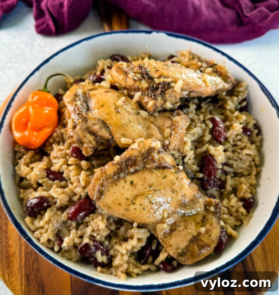 jerk chicken, rice, peas, red beans, and peppers in a white bowl