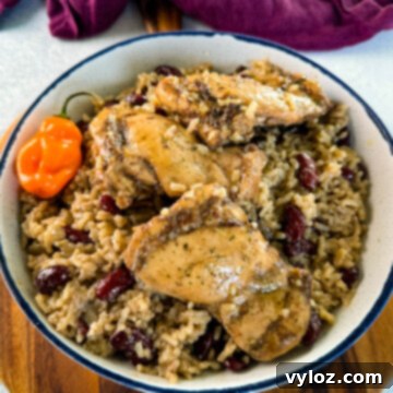 jerk chicken, rice, peas, red beans, and peppers in a white bowl