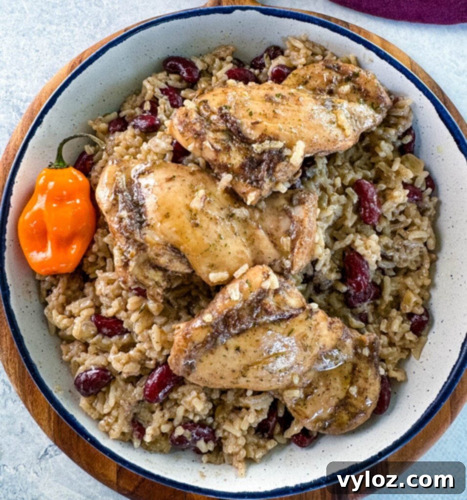 jerk chicken, rice, peas, red beans, and peppers in a white bowl