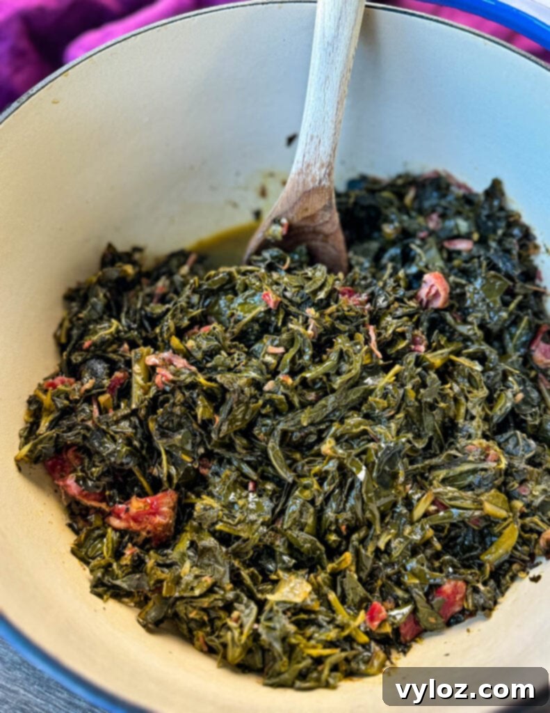 collard greens and ham hocks in a Dutch oven with a wooden spoon