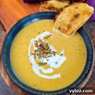 Creamy butternut squash soup in a bowl with cream, nuts, and toasted bread