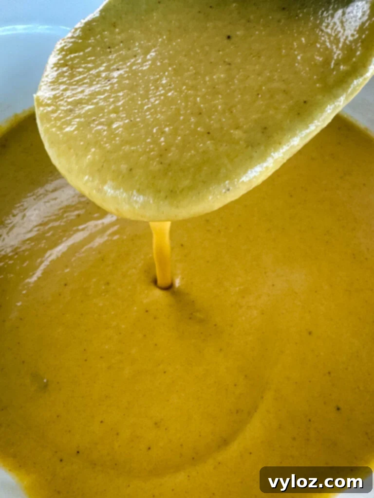 A wooden spoonful of creamy butternut squash soup, showing its smooth texture